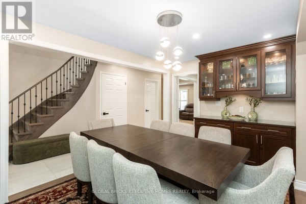 Dining room with large table, chairs, buffet, chandelier, and curved staircase - 5952 Grossbeak Drive Mississauga