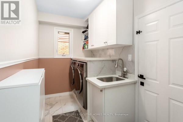 Laundry room with washer/dryer, sink, and white cabinets - 5952 Grossbeak Drive Mississauga