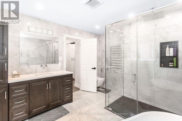 Modern bathroom with double vanity, walk-in shower, rainfall showerhead, heated towel rack, and soaking tub - 5952 Grossbeak Drive Mississauga