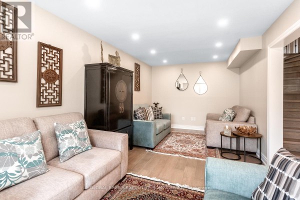 Neutral sofas, large black cabinet, decorative mirrors, and oriental rugs in a living room - 5952 Grossbeak Drive Mississauga