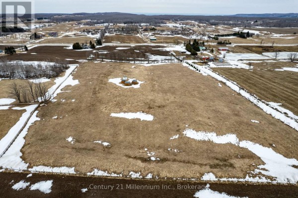 Aerial view of cleared farmland with brown soil and scattered snow in the foreground. - 595298 4th Line, Blue Mountains