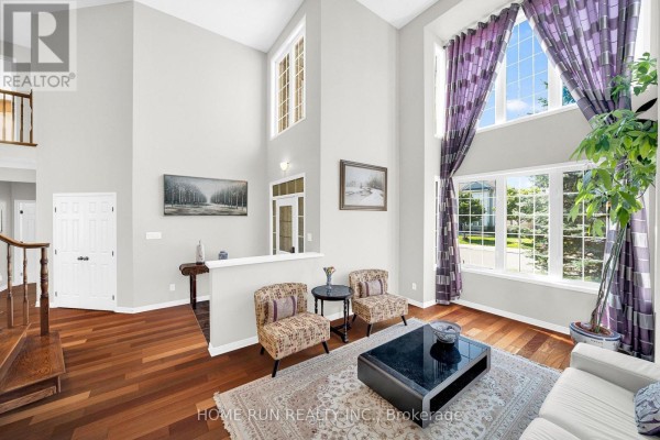 Spacious living room with hardwood floors, a white sofa, a dining room area, and a curved staircase. - 596 Anjana Circle, Ottawa