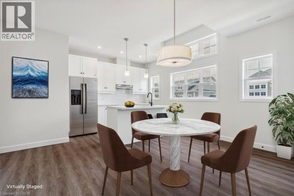 Open concept dining area and kitchen with white cabinetry, stainless steel appliances, and a marble dining table. - 5b Shores Lane, Crystal Beach