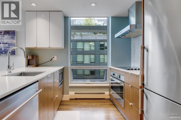 Modern kitchen with stainless steel appliances, wood cabinets, and blue walls. - 5xx 159 2nd Avenue, Vancouver