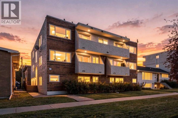 Apartment building exterior at dusk with glowing windows and a colorful sky. - 6, 1905 11 Avenue Sw, Calgary