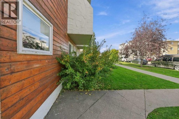 Close-up of the wood siding and green bushes on the side of an apartment building. - 6, 1905 11 Avenue Sw, Calgary