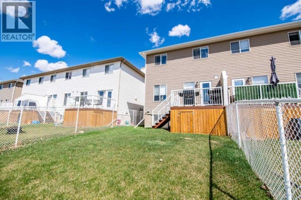 Backyard deck stairs leading to a grassy area with a barbecue and distant view. - 6, 2002 22 Avenue, Bowden