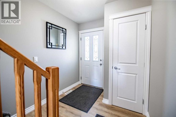 Interior entryway with light wood railings, a black rug, and white doors. - 6, 2002 22 Avenue, Bowden
