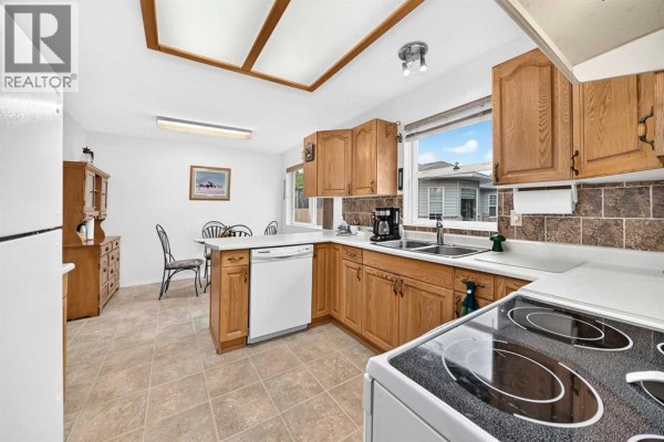 Kitchen with light oak cabinets, white countertops, and view to dining area. - 6, 6500 40 Avenue, Stettler