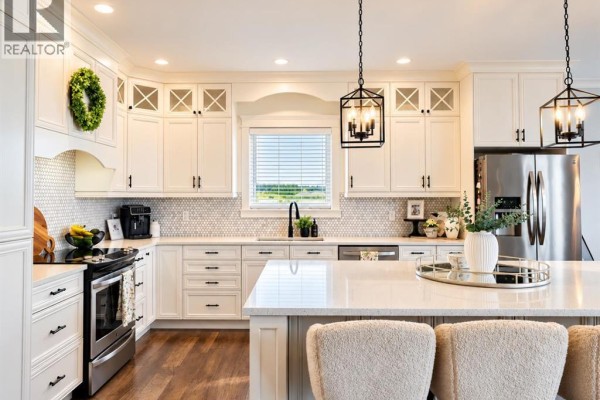 Modern white kitchen with a large island, stainless steel appliances, and a view of a field. - 6, 715034 Range Road 73, Rural Grande Prairie No  1, County Of