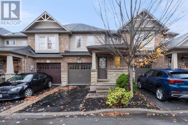 Townhouse exterior with neutral brick and siding, covered porch, and garage doors. - 6 - 10 Pumpkin Pass, Hamilton