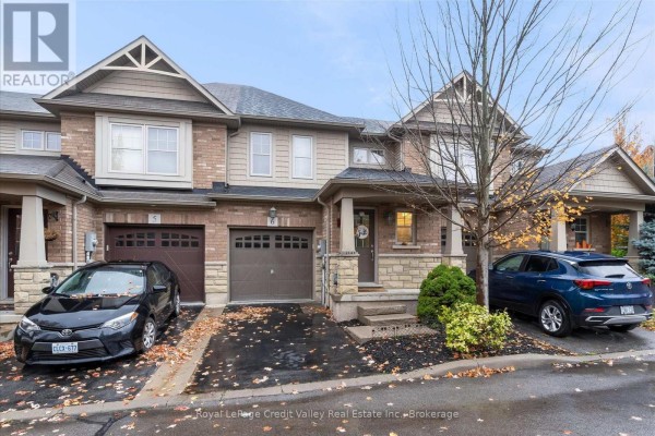 View of the front exterior of a brick and siding townhouse, with two cars parked. - 6 - 10 Pumpkin Pass, Hamilton