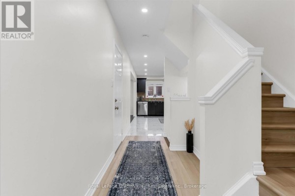 Interior hallway with white walls, wood floors, a runner rug, and staircase. - 6 - 10 Pumpkin Pass, Hamilton