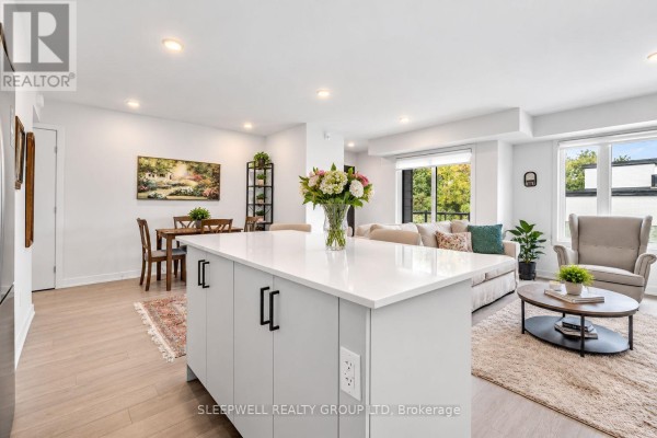 View of the living and dining area from the kitchen island, showing a sofa, chairs, dining table, and large windows. - 6 - 152 Springhurst Avenue, Ottawa