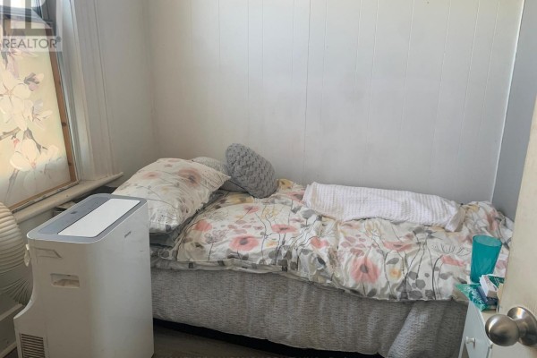Small bedroom with a single bed, floral bedding, and a white portable air conditioner. - 6 - 2 Bascom Street S, Uxbridge