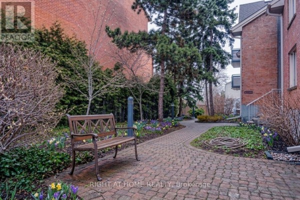 Garden pathway with bench, bordered by snow and greenery, leading to the townhouse entrance. - 6 - 2 Columbus Avenue, Ottawa