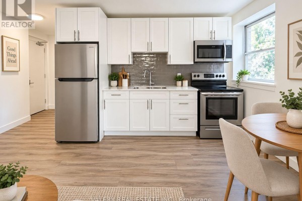 Modern white kitchen with stainless steel appliances and light wood laminate flooring. - 6 - 20 Craig Street, London South