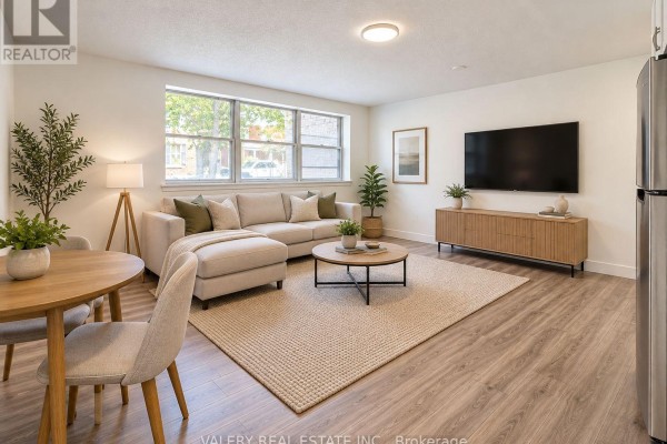 Living room with a beige sectional sofa, round coffee table, wood media console, and large window. - 6 - 20 Craig Street, London South