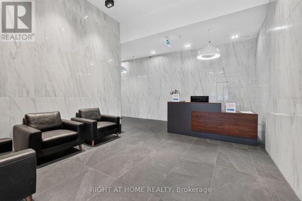 Lobby with grey tile floor, marble-patterned walls, and black leather chairs. - 6 - 203 Catherine Street, Ottawa