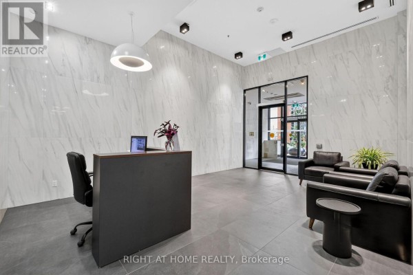 Reception desk area in a modern lobby with seating and marble walls. - 6 - 203 Catherine Street, Ottawa