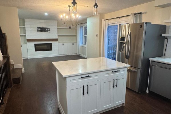Open concept living area with a fireplace, built-in shelves, and a kitchen island. - 6 - 230 Clarke Road, London East