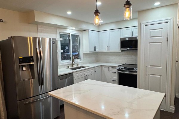 View of the kitchen featuring white cabinets, stainless steel refrigerator, sink, and quartz countertops. - 6 - 230 Clarke Road, London East