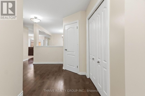 Interior hallway with dark hardwood floors, a white closet, and a view of an open-concept living space. - 6 - 400 Skyline Avenue N, London North