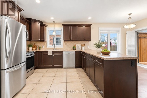 Kitchen with dark wood cabinets, stainless steel appliances, beige tile flooring, and granite countertops. - 6 - 400 Skyline Avenue N, London North