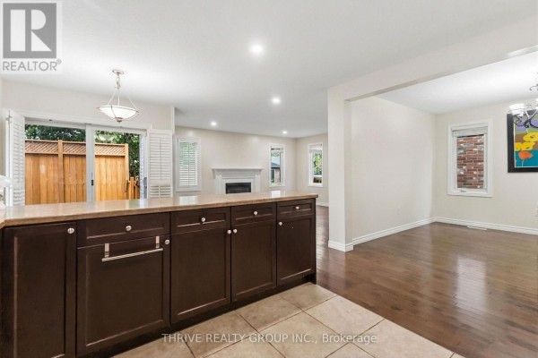 View from kitchen island to open-concept living and dining room with a fireplace and large windows. - 6 - 400 Skyline Avenue N, London North