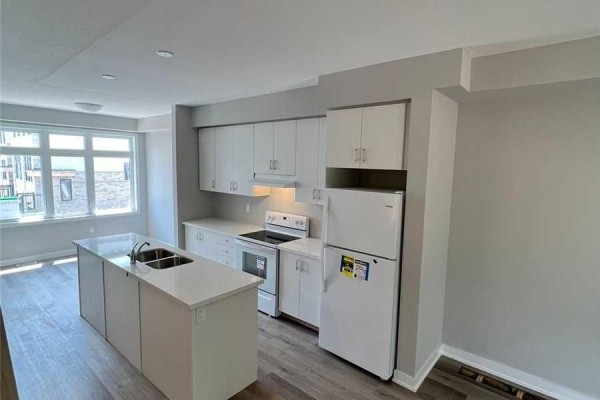 Kitchen with white cabinets, island, stainless steel appliances, and wood-look flooring. - 6 - 527 Shaver Road, Hamilton