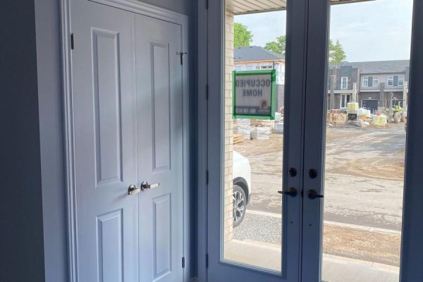 View from inside through double glass doors to a construction site with building materials and a white car. - 6 - 5672 Dorchester Road, Niagara Falls