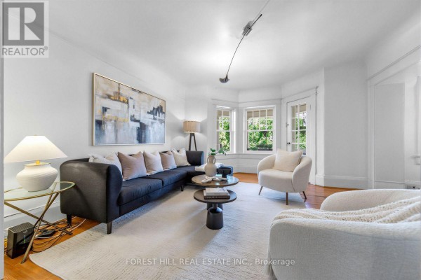 Living room with a large sectional sofa, abstract art, bay windows, and white chairs. - 6 - 68 Kendal Avenue, Toronto