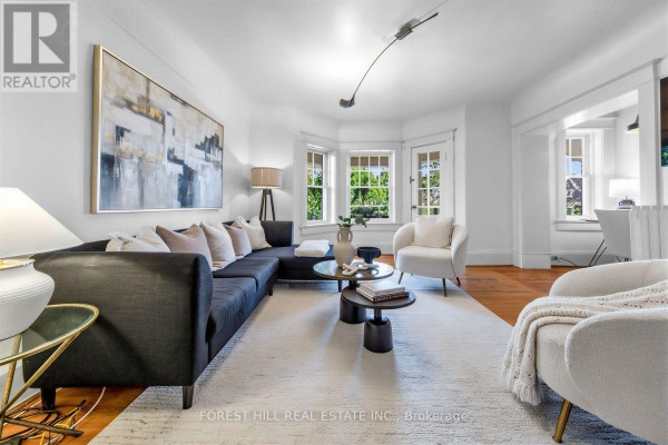 Living room with a sectional sofa, abstract art, bay windows, and a dining area. - 6 - 68 Kendal Avenue, Toronto