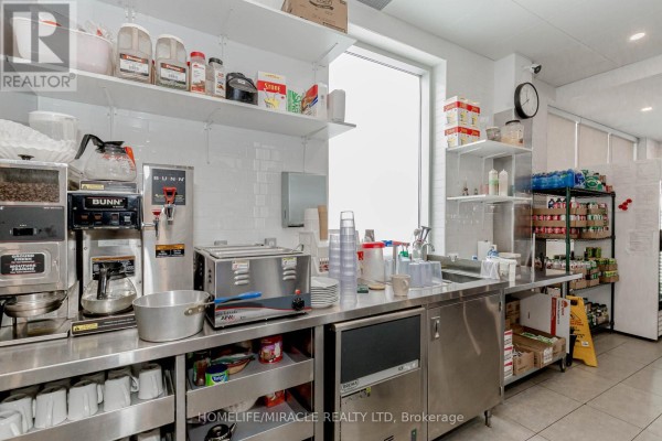 Counter area with coffee machine, toaster, sink, and shelves holding cups and condiments. - 6 & 7 - 1840 Major Mackenzie Drive, Vaughan