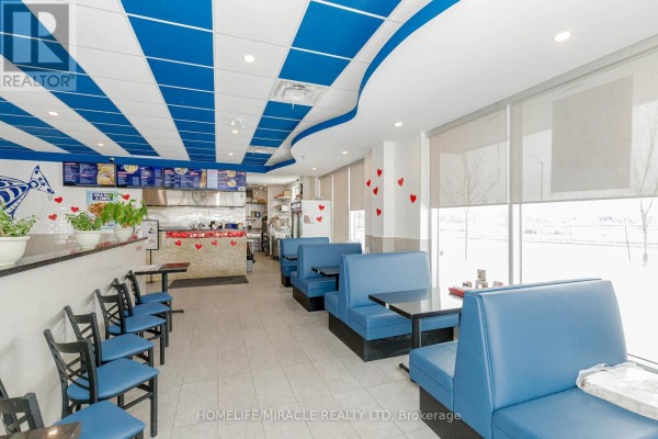 Restaurant seating area with blue booths, black tables, and chairs, adjacent to the kitchen. - 6 & 7 - 1840 Major Mackenzie Drive, Vaughan
