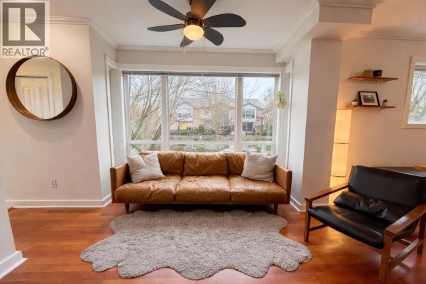 Cozy corner with a leather couch, ceiling fan, and large windows for natural light. - 6 1233 Main Street, Squamish