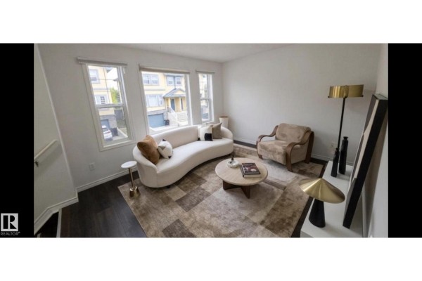 Living room with white sectional sofa, armchair, coffee table, and large window. - #6 16777 91 St Nw Nw, Edmonton