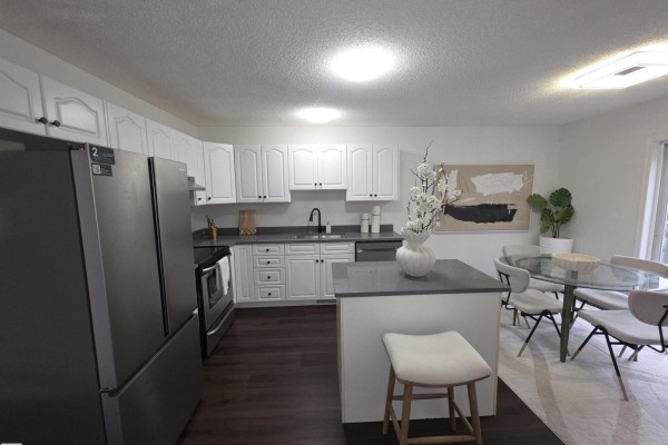 Kitchen with white cabinets, grey countertops, stainless steel appliances, and dining area. - #6 16777 91 St Nw Nw, Edmonton