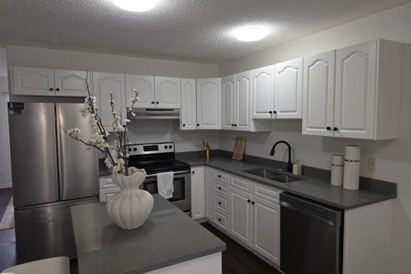 Kitchen with white cabinets, grey counters, stainless steel appliances, and island with seating. - #6 16777 91 St Nw Nw, Edmonton