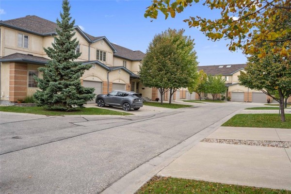 Street view of townhouses on Shorehill Drive, Winnipeg with mature trees and blue sky. - 6 25 Shorehill Drive, Winnipeg