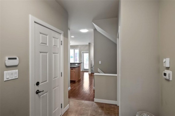 Interior hallway with tiled floor, white doors, and view of a kitchen and staircase. - 6 25 Shorehill Drive, Winnipeg