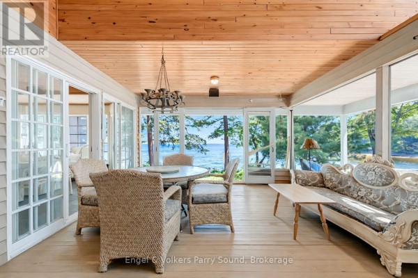 Screened-in porch with wicker furniture, a dining set, and a sofa overlooking the water. - 6 29c Mowat Island, Carling