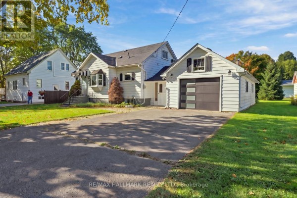 Side view of a white bungalow with a detached garage and driveway, showing a person walking on the lawn. - 6 Albert Street, Whitby