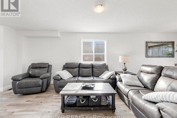 Living room with grey leather seating, a dark wood coffee table, and a window. - 6 Booth Lane, Barrie