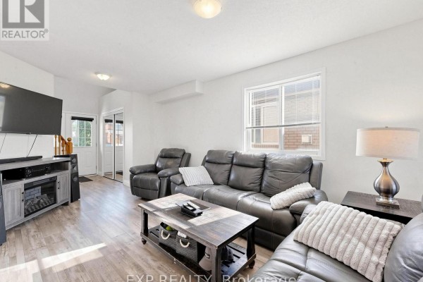 Living room with a television, grey seating, and a door leading outside. - 6 Booth Lane, Barrie