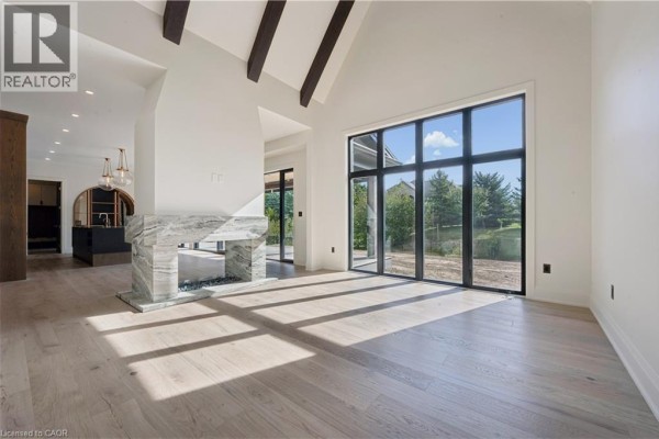 Spacious living room with vaulted ceiling, exposed beams, marble fireplace, and large windows. - 6 Bridlewood Crescent, Kitchener