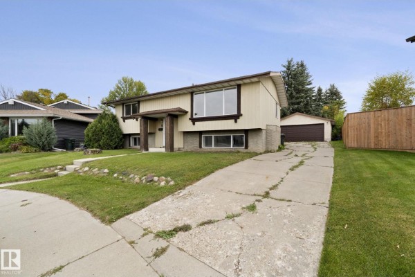 View of the side and back of a split-level home with a detached garage and driveway. - 6 Campbell Cres E, Stony Plain