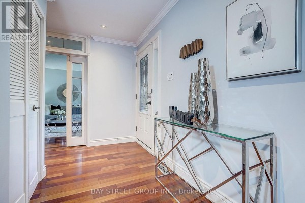 Interior hallway with light blue walls, hardwood floors, and a glass console table. - 6 Caravan Drive, Toronto