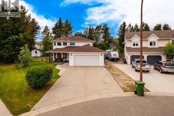 Aerial view of 6 Carnelian Court with a long driveway, mature trees, and neighboring houses. - 6 Carnelian Court, Whitehorse