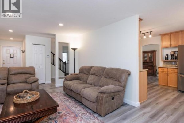 Living room with two brown sofas, a coffee table, and view into the kitchen with light wood cabinets. - 6 Carnelian Court, Whitehorse